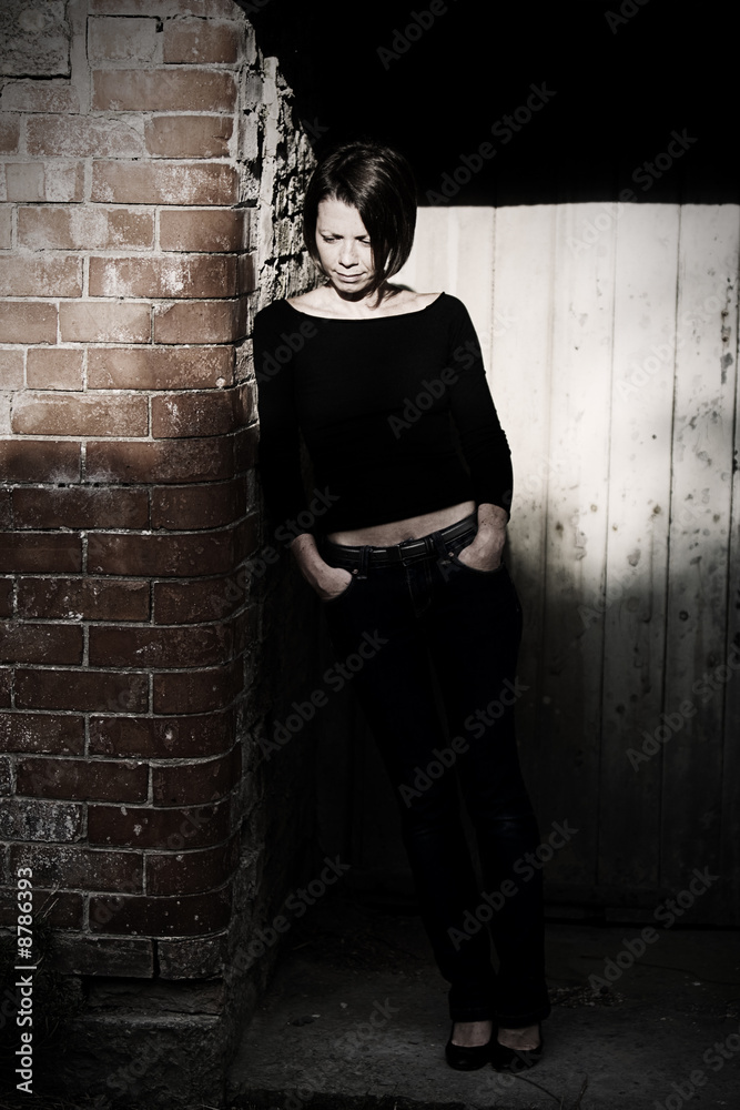Attractive Brunette in Shadows against Red Brick Wall and Door