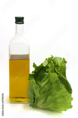 olive oil in transparent bottle with green salad