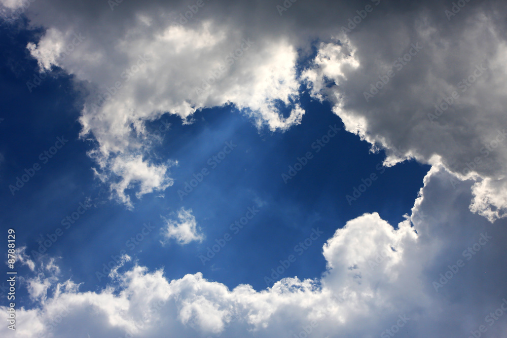 fantastic cloudscape on a blue sky, sun shining behind