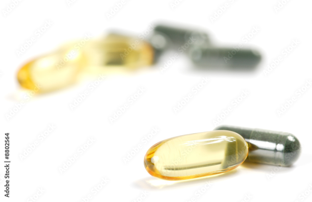 Transparent cod-liver pill and dark pill on a white background Transparent cod-liver pill and dark pill on a white background