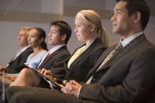 Tableau sur toile Five businesspeople sitting in presentation room with clipboards