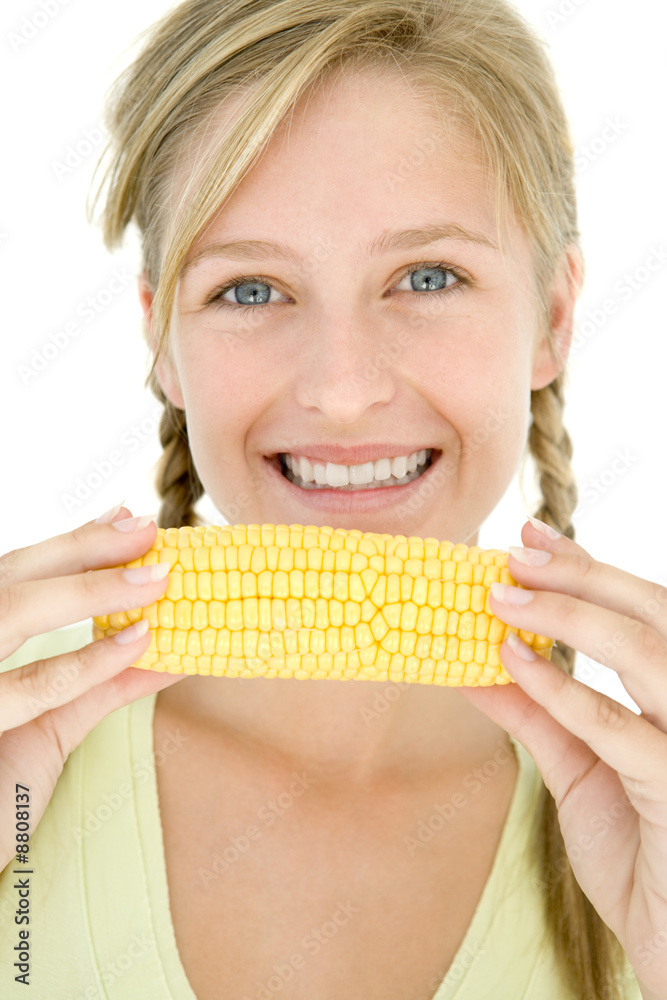 Teenage girl holding corn on cob and smiling Teenage girl holding corn on cob and smiling