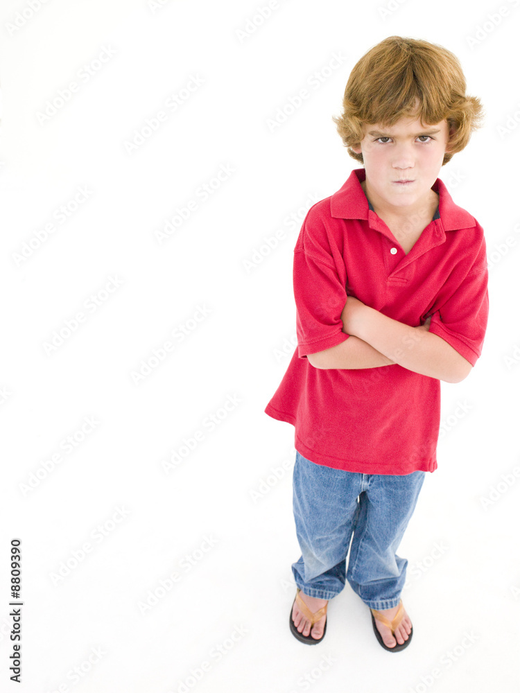 Young boy with arms crossed scowling