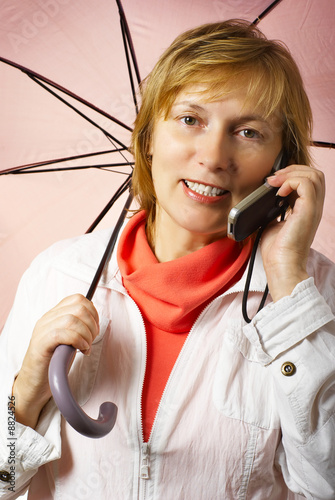 Middle years woman under the umbrella  speaks mobile phone