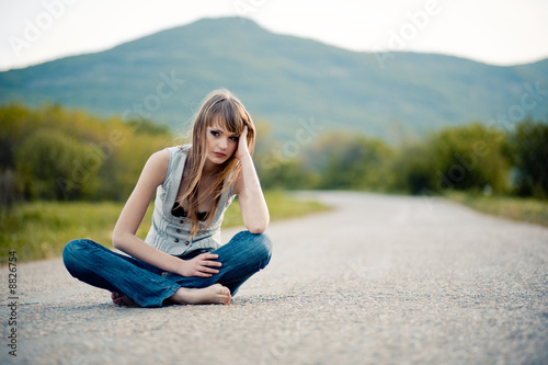 Tired young girl sitting down on road