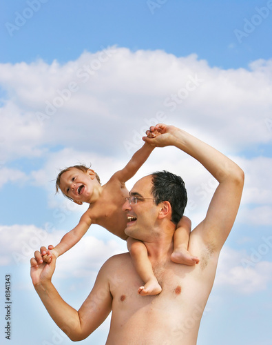 father and son playing on beach on sky background