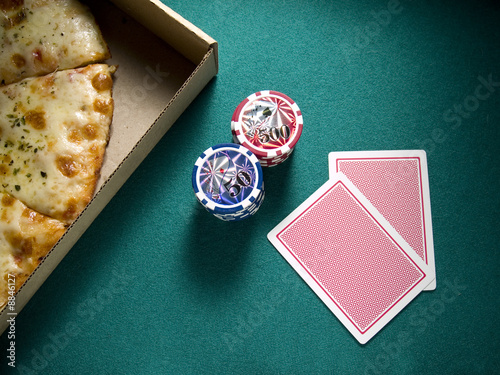 Cards, chips and a box of pizza over a green felt.