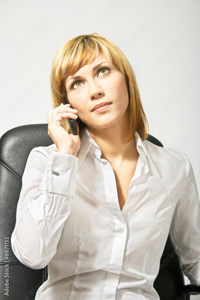 Young beautiful business lady on a chair speaking by phone. Young beautiful business lady on a chair speaking by phone.