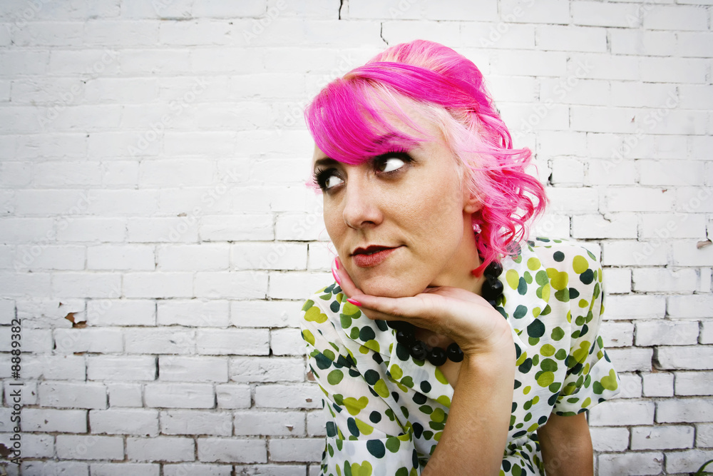 Woman with pink hair in front of white painted brick wall Woman with pink hair in front of white painted brick wall