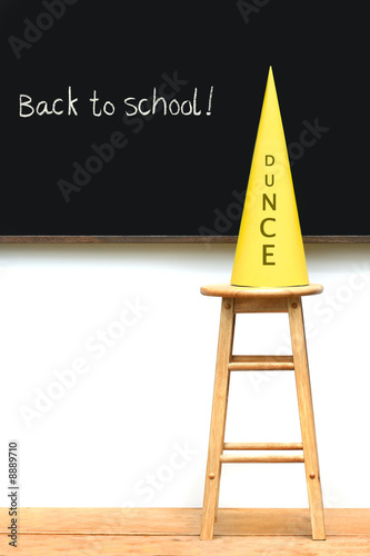 Yellow dunce hat on stool with chalkboard