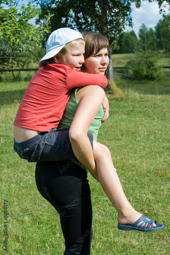 Happy mother giving her son a piggyback ride in the city stock photo