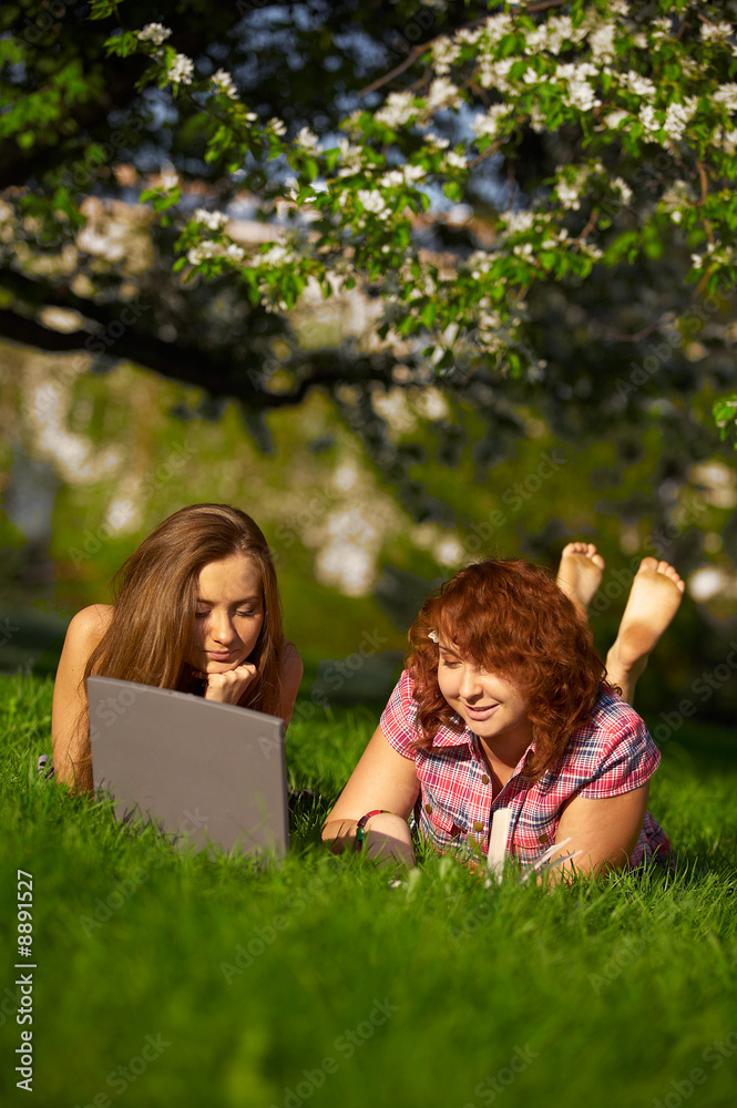 two student girls studying outdoors on grass two student girls studying outdoors on grass