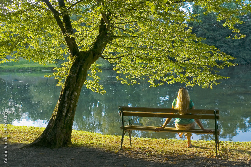 Girl sitting under a tree by the river.
