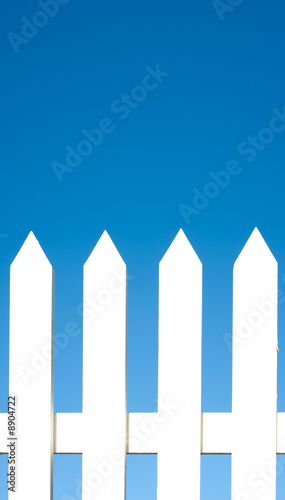 A white picket fence background in front of a bright blue sky