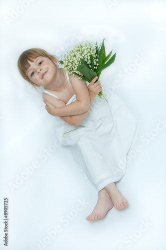 little, pretty girl holding bunch of lilies of the valley