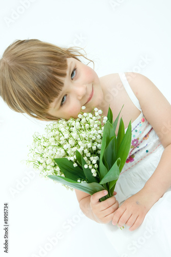 little, pretty girl holding bunch of lilies of the valley