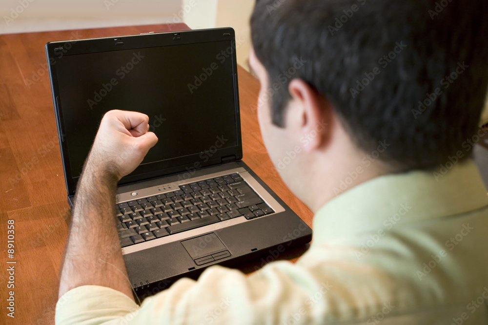 A young business man getting frustrated with his laptop. A young business man getting frustrated with his laptop.