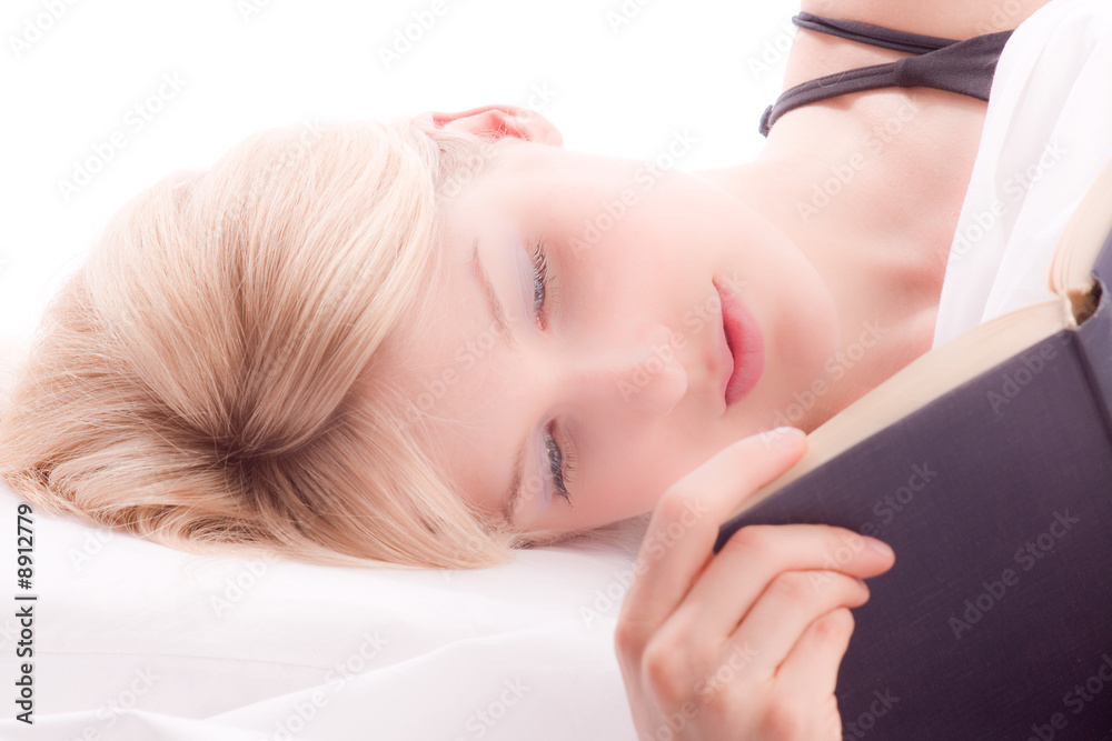 Obraz premium young blond woman reading a book in bed