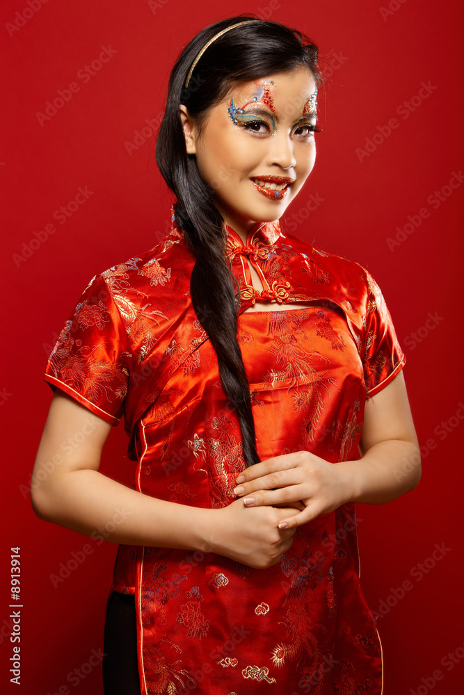 Beautiful Asian girl as a plastic doll on red background Beautiful Asian girl as a plastic doll on red background
