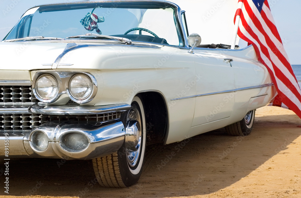 Naklejka premium Klasyczny biały Cadillac na plaży z amerykańską flagą
