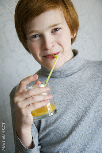 The red boy drinks juice