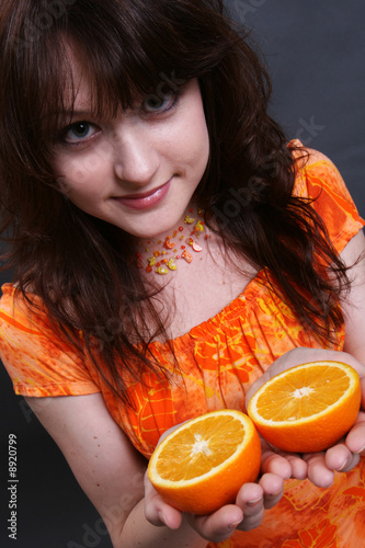 The positive smiling girl with an orange in hands