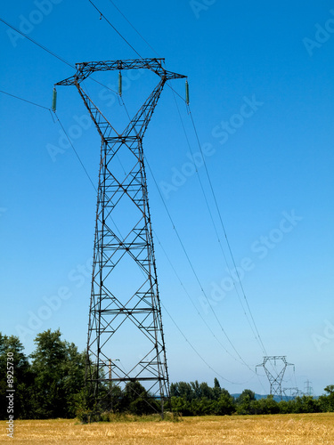 High voltage electricity pylons under blue sky