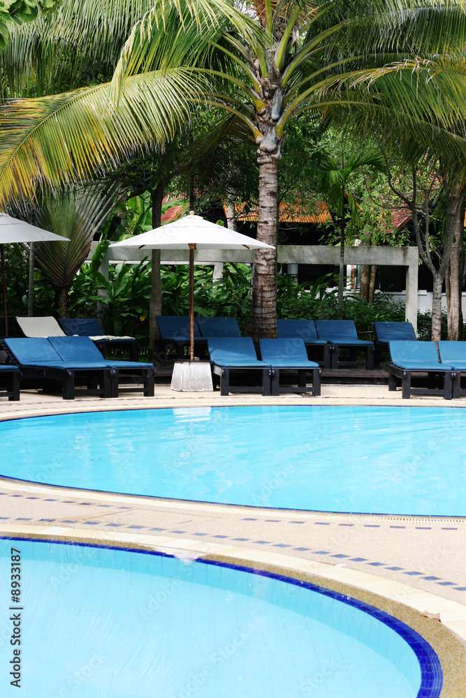 Deck chairs and umbrellas next to a swimming pool.