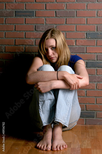 woman looking vulnerable and sitting with knees up