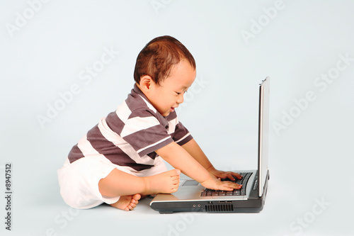 A happy toddler learn how to use a laptop computer photo