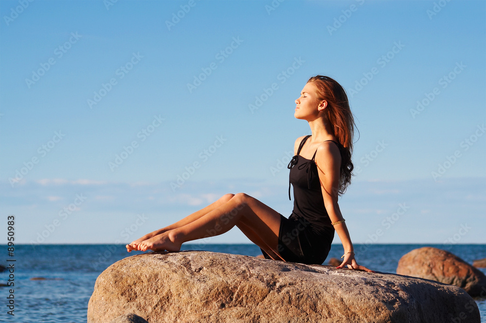 Young girl sitting on a stone and enjoying the sun