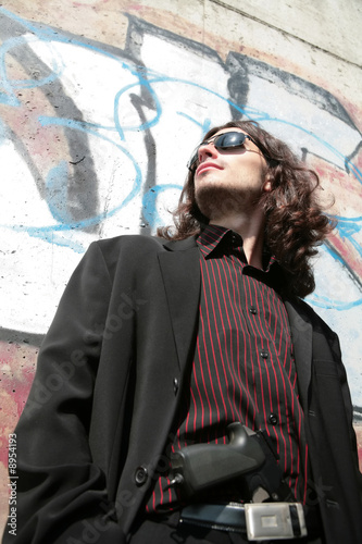 young man with gun and in black sunglasses in gangster style photo