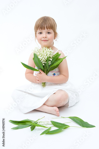 little, pretty girl holding bunch of lilies of the valley
