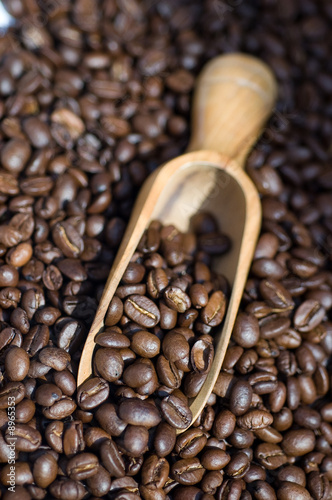 Close up of coffee beans spilling out of wooden scoop
