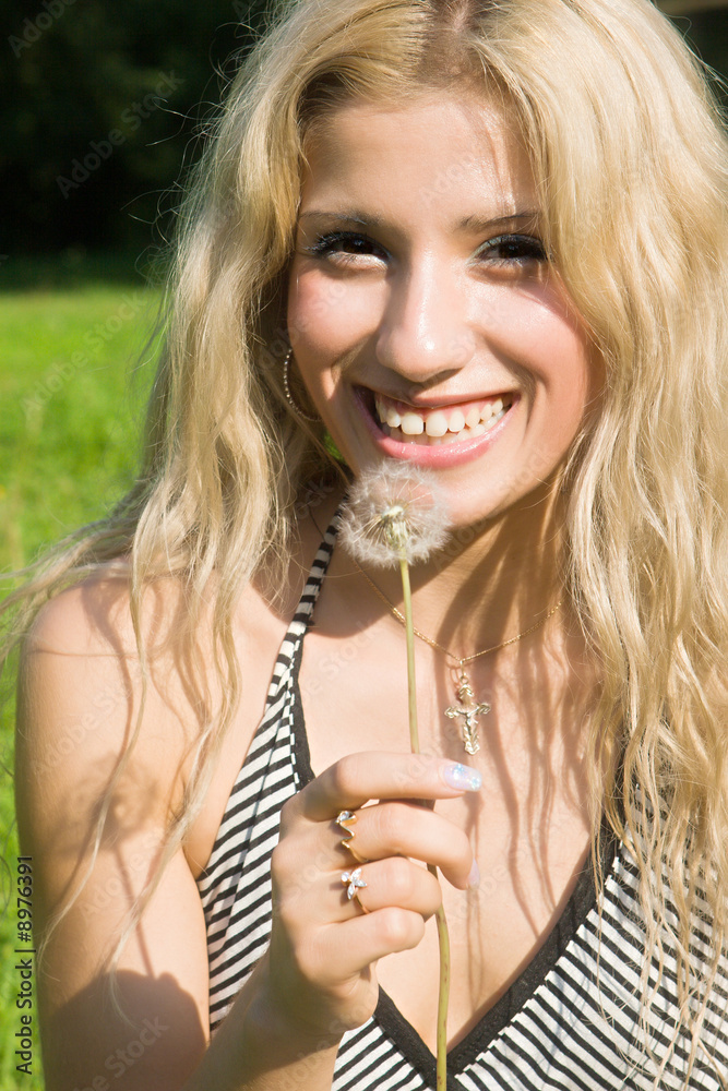 Beautiful girl with a dandelion in a hand
