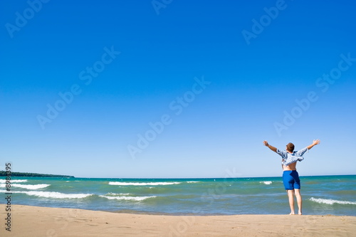 Man with arms outstretched standing on the lakeshore