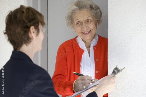 Attractive senior woman signing a document at front door