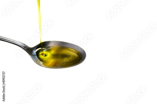 olive oil pouring into a spoon, on white
