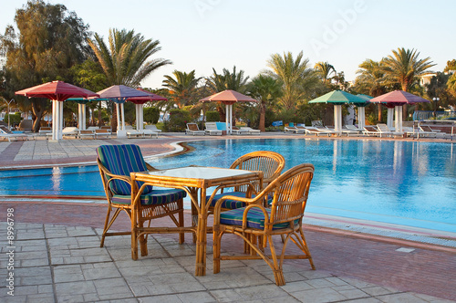 Three arm-chair and one table near swimming pool.