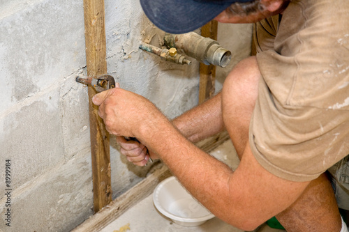 Plumber using channel-lock pliers to attach a nut to a pipe