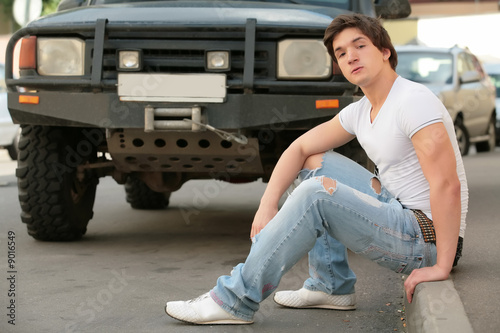 man in white t-shirt and blue jeans near black jeep