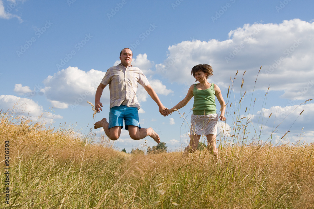 happy couple jumping together on a summer day happy couple jumping together on a summer day