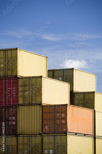 shipping freight containers stacked in port against blue sky