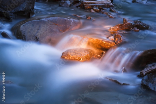 blue river stream at night with golden light on rocks