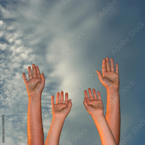 hands raised to sky at sunset