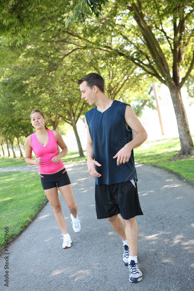 An attractive man and woman couple jogging in the park
