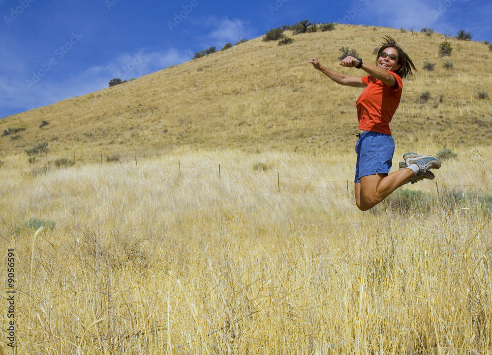 girl jumping in a field in the hills girl jumping in a field in the hills