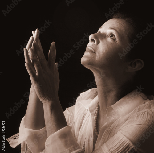 Woman with hands folded in prayer, looking up to the Light photo