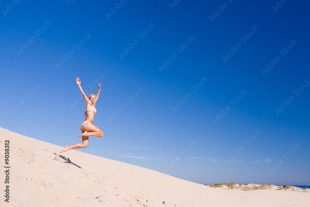 beautiful female exercising on the sand dunes