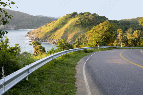 Winding road with sea view and mountains.
